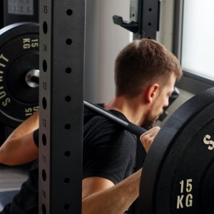 Physiotherapeut Matthias führt Kniebeugen mit Langhantel durch